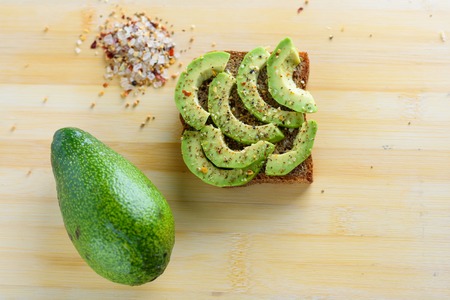 Spicy avocado toast - healthy breakfast. Beautifully rye toast bread with sliced green avocado, lime...