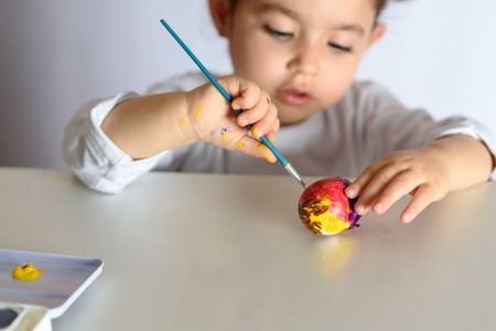 Happy easter. Funny little girl painting Easter eggs. Happy toddler preparing for Easter.の写真素材