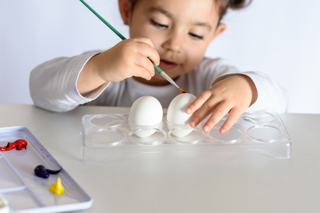 Happy easter. Funny little girl painting Easter eggs. Happy toddler preparing for Easter.の写真素材