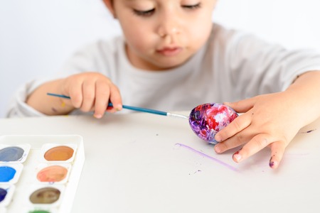 Happy easter. Funny little girl painting Easter eggs. Happy toddler preparing for Easter.