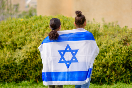 Two patriot jewish teenager girl standing and enjoying with the flag of Israel on nature background.Memorial day-Yom Hazikaron, Patriotic holiday Independence day Israel - Yom Haatzmaut concept.の写真素材