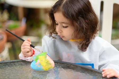 Portrait of little child painting, summer outdoor.Kid drawing on a stone.の写真素材