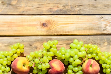 First fruits habikkurim in hebrew on wooden rustic table. Symbols of jewish holiday - Shavuot. Grapes and peaches on wood vintage background.の写真素材