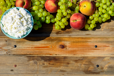 Plate of homemade cottage cheese, grapes and peach on wooden rustic table.Copy space for text.の写真素材
