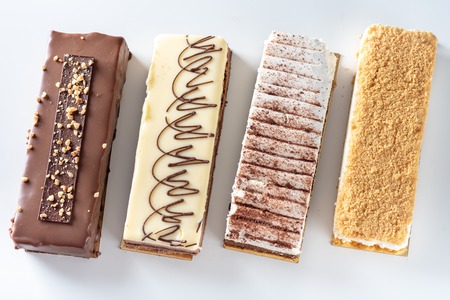 Beautiful Delicious dessert cheesecakes and chocolate cake on a white table from above. Group of...