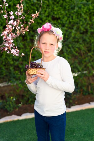 Little young beautiful cute sweet pretty happy girl portrait with basket of fresh grapes in the spring garden.の写真素材