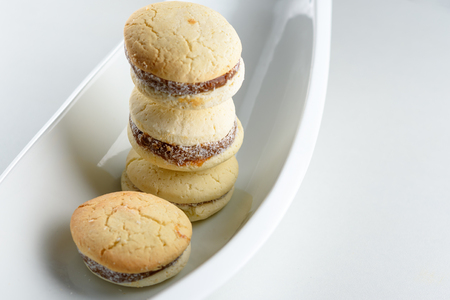 Delicious Argentinian cookies alfajores with cream dulce de leche close-up on the table. White vanilla macaroons on white background. French delicate dessert for Breakfast in the morning light.の写真素材