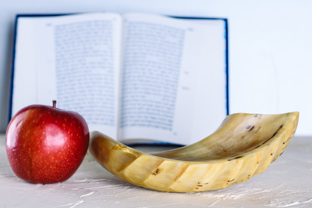 Rosh Ha Shana - Jewish new year composition of an red apple, Torah and Shofar horn for Rosh Hashanah on white modern putty background.の写真素材