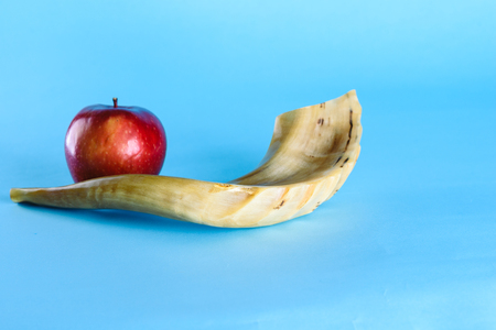 Rosh Ha Shana - Jewish new year composition of an red apple and Shofar horn for Rosh Hashanah on blue background.Jews dip a slice of apple in honey to express hopes for a sweet and fruitful year.の写真素材