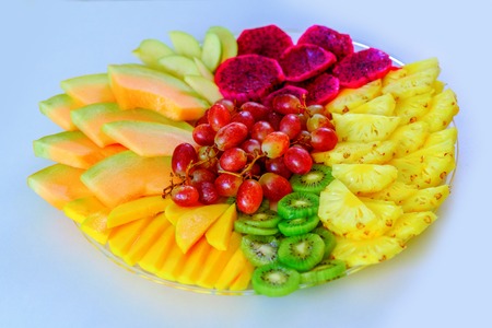 Colorful, healthy foods great idea for good nutrition, vitamins gift for holidays. Fruit tray red pitaya dragon fruit, pineapple, grapes, mango, melon, kiwi on plate on white table.Flat lay, overhead.の写真素材