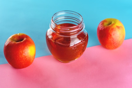 Apples and honey jar for jewish new year holiday Rosh Hashanah over blue pink background. Healthy food.の写真素材