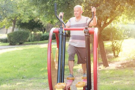 Happy older man working out on the sports public equipment in the outdoor gym.A sportive active...