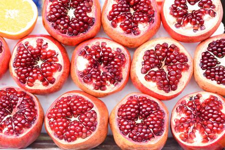 Juicy pomegranates with seed and half fleshy orange background.の写真素材