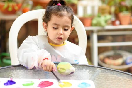 Portrait little child painting, summer outdoor. Girl drawing on a stone.の写真素材