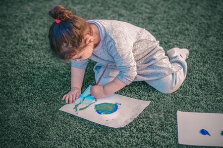 Beautiful little girl drawnig a picture of earth globe. Child painting with brush and color a picture of earth.Earth day, plastic free and zero waste concept.の写真素材