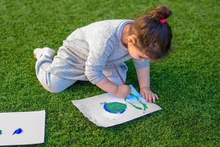 Beautiful little girl drawnig a picture of earth globe. Child painting with brush and color a picture of earth.Earth day, plastic free and zero waste concept.の写真素材