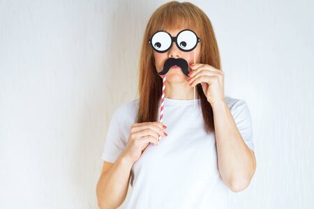 Attractive middle aged woman having fun with a fake moustache and glasses. A senior female in the period of menopause. Lifestyle, woman health concept : playful Blond red hair mature ready for partyの写真素材