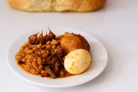 Challah Shabbat bread and hamin or cholent in hebrew - Sabbath traditional food on white table in the kitchen.の写真素材