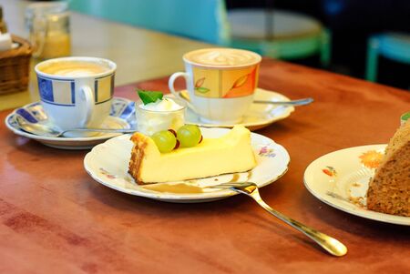 Beautiful, cheesecake with berries, and cream decorated with mint leaves served in magnificent crockery on a wooden table.の写真素材