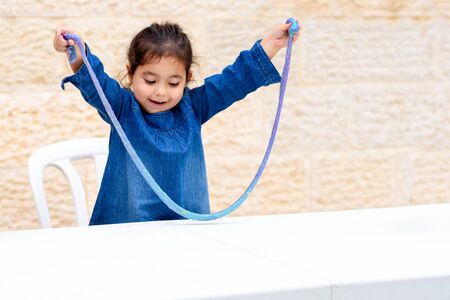 Smiling,laughing toddler girl playing with blue slime.