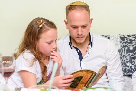 Jewish family celebrate Passover Seder reading the Haggadah. Selective focus on man.の写真素材