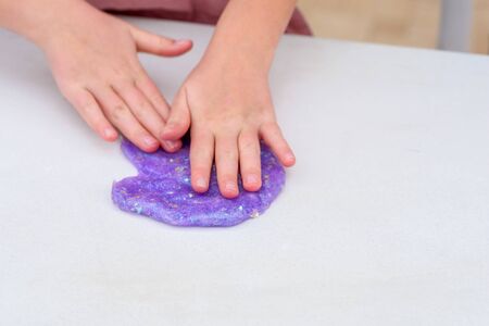 Process of making slime. Purple magic glitter slime on a white background. Child crumples slime....