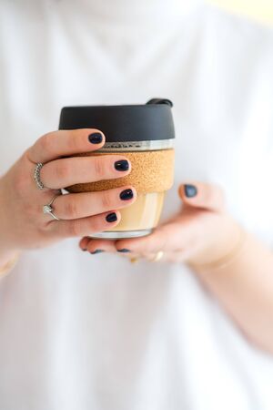 Woman hands hold reusable glass coffee cup. Sustainable living. Eco friendly, zero waste concept.