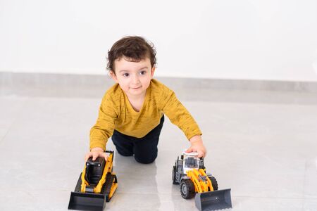 Little boy plays with toy cars. Happy kid playing with tractor car toy at home.の写真素材