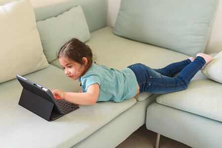 Little preschool girl video chat with the teacher online. Home school, distance learning, video call at home.の写真素材