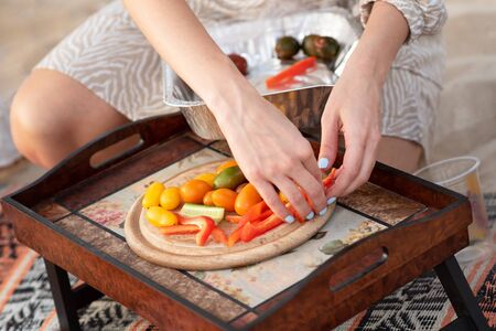 Group of friends having a picnic at the beach. Woman serving food to her friends, or family...