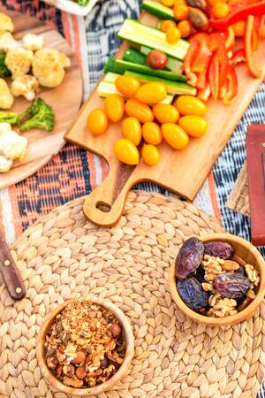 Beautiful summer picnic on the beach at sunset in zero waste style. Organic fresh vegetables, date and granola in wooden bowls, top view. Eco friendly idea for weekend picnic.の写真素材