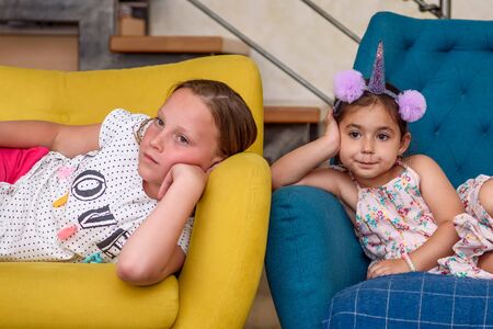 Little girls lying on the sofa and watching TV together.の写真素材