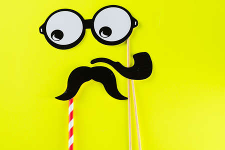 Top view image of funny masks glasses, smoking pipe and mustache on yellow background. Party,...
