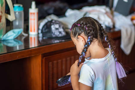 Image of a young girl getting her hair combed and braided.
