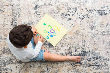 Cute little boy making Christmas cards at home. Toddler making care package at home.