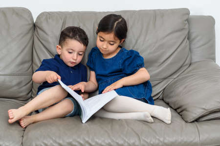 Family quality time together. Immediate family members, inside the home reading a book. Quality time...