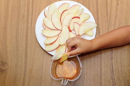 Closeup of childrens hand dipping apple slices into honey on Rosh HaShanah the Jewish New Year.の写真素材
