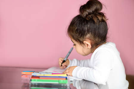 Little cute girl drawing, cozy moment of life. Back to school or preschool, home learning. Adorable child painting at table. Selective focus.の写真素材