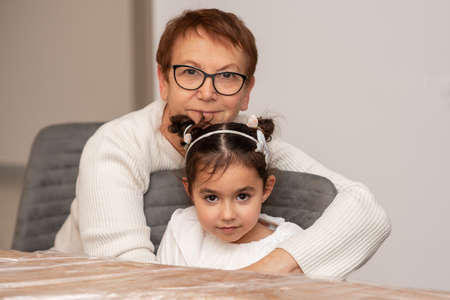Close up family portrait of happy two generations of senior woman and her grandchild. Smiling little...