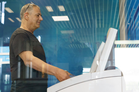 Senior man withdrawing money at an ATM in the city. Confident old business man using credit card...