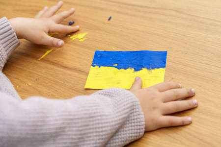 Support for Ukraine. Close up child hands sculpts from colored plasticine Ukraine flag. Concept of patriotism, respect, charity, help, and solidarity with the citizens of Ukraine.の写真素材