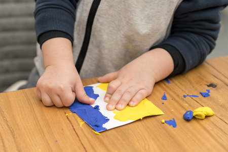 Support for Ukraine. Close up little child hands makes Ukraine flag out of plasticine. Concept of patriotism, respect, charity, help, and solidarity with the citizens of Ukraine.の写真素材
