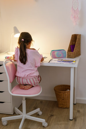 Schoolgirl sitting at desk and writing notes on notebook.の写真素材