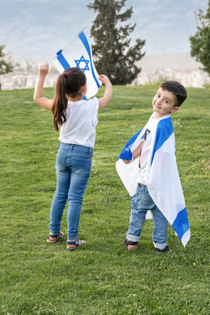 Young Children With Israeli Flag. Rear View Faceless Little Girl And Smile Boy With Israel Flag In The Park. Go Vote Elections Concept. Presidential Elections In Israel.の写真素材