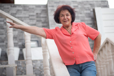 Happy smiling senior mature woman standing on a staircase.の写真素材