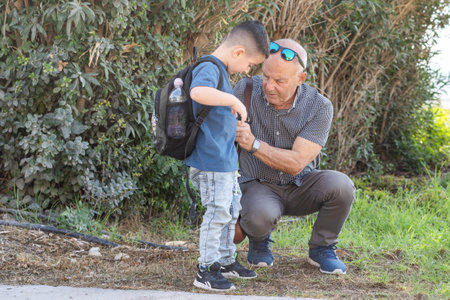 Grandfather and grandson hiking. Happy senior grandfather helping her little grandson with backpack before school outdoors.の写真素材