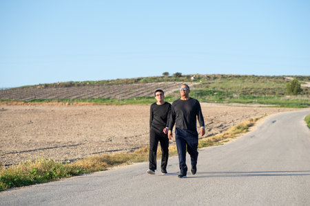 Middle age father and teenager son hikers in nature, walking outside on a sunny spring day. Young...