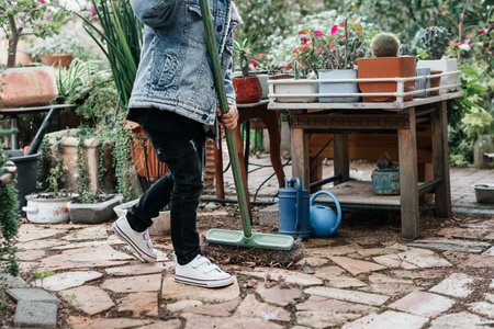 A faceless child sweeping leaves at the backyard in the morning.の写真素材