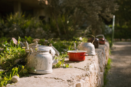 Vintage Teapots and Pots into Garden Design on Sunny Day. Bright Sunlight Highlights the Rustic and...
