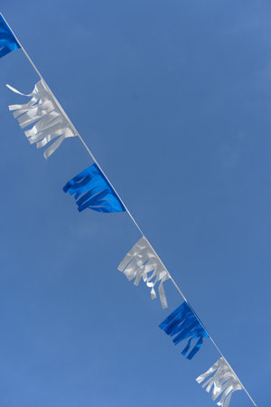 Israeli blue and white flag bunting fluttering against a backdrop of blue sky with white clouds on Independence Day of Israel. Perfect for projects related to Israeli culture and celebrations.の写真素材
